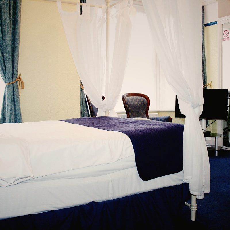 Four-poster style bedroom with navy throw